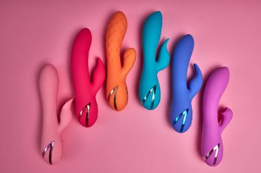 Bright Colorful G-spot Vibrators Arranged On Pink Paper Background, Big Variety Of Dildo Colours