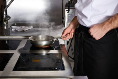 Mutfak restoranında aşçı, ocakta yemek hazırlıyor.