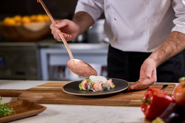 Kırpılmış şef salataya eksik malzemeler ekliyor.