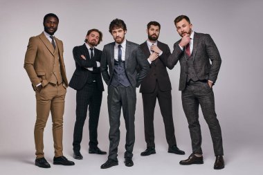 Diverse brutal men in classic suit looking at camera posing clipart