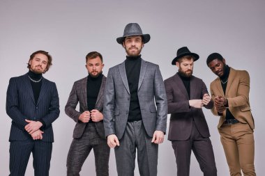 Patron ve arkadaşları kameraya karşı klasik takım elbise ya da smokin giyer.