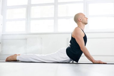 Yoga. Beyaz arka planda yoga egzersizi yapan kel bir genç.