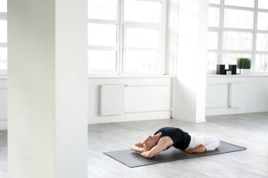 Spor yapan genç bir adam, esnek omurga ve tüm vücut için egzersiz yapıyor.