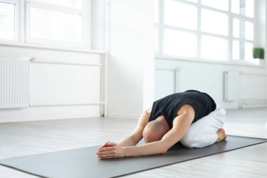 Sportif adam Hatha yoga eğitmeni. Uzatılmış çocuk pozu. Utthita Balasana öne doğru eğiliyor.