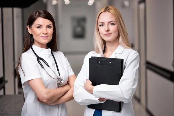 젊고 확신에 찬 두 명 의 코카서스 여성 의사들 이 카메라 로 병원 강당을 방문하다 — 스톡 사진