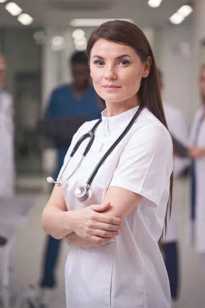 흰색 유니폼을 입고 카메라 앞에 포즈를 취하는 매력적 인 코카서스의 자신감 있는 의사 — 스톡 사진