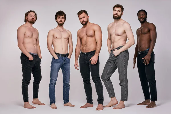 Confident fit guys with naked torso posing together, having serious look