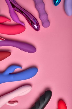 Pembe arka planda bir sürü renkli dildo var. İmaj, seks mağazası reklamları için uygundur