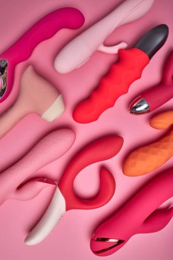 Pembe arka planda farklı kırmızı ve pembe yetişkin seks oyuncakları