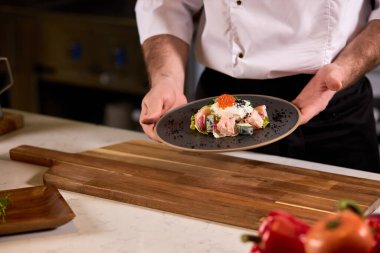 Bak şimdi. Şef tabakta pişmiş yemeği, taze salatayı gösteriyor.