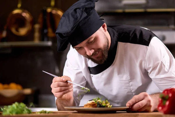 Chef finishing dish on plate with dish dressing and almost ready to serve at table