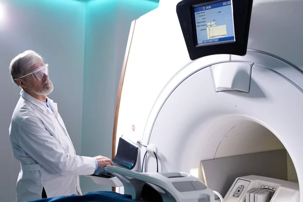 Orvosi laboratóriumban vezető radiológus-kontroll MRI vagy CT vagy PET vizsgálat férfi betegnél eljárás alatt — Stock Fotó