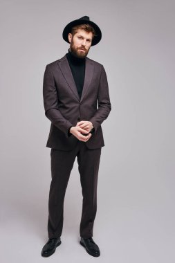 Fotoğraf makinesine poz veren zarif takım elbiseli beyaz sakallı genç adamın portresi.