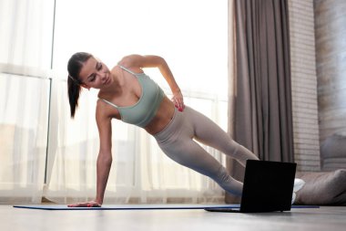 Evde dizüstü bilgisayar kullanarak harika formda bayan eğitimi.