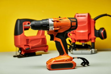 Tornavida, arka planda yapboz olan kırmızı pil matkabı.