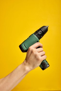 Sarı arkaplan üzerinde izole pilli tornavida veya matkap