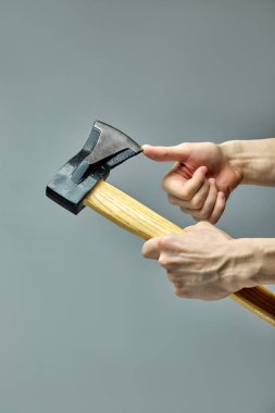 Tanımlanamayan adam baltanın keskinliğini parmak ile kontrol eder.