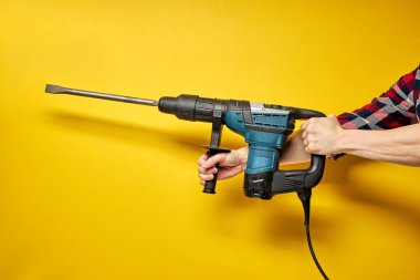 Sarı arka planda izole edilmiş inşaatçının ellerinde yeşil yumruklayıcı