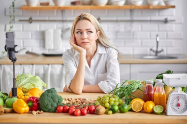 Diyet kavramı. Sağlıklı genç bir kadın. Şüphe ediyor ve kafası karışık. Mutfaktaki bir şey için endişeleniyor.