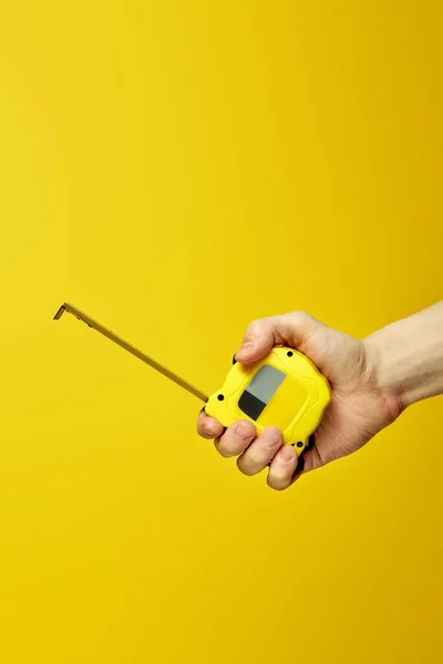 Single yellow tape measure, isolated over yellow background