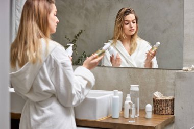 Güzel sarışın kadın seçer, kozmetik ürünlerini karşılaştırır, hangisi daha iyi olur?