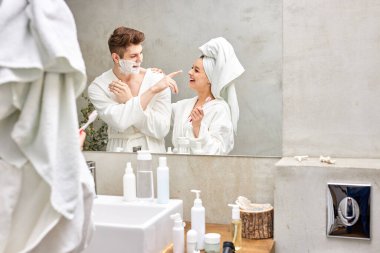 20-26 yetişkin çift eğleniyor, dişlerini fırçalamayı seviyor ve diğer sabah ameliyatlarını banyoda yapıyor.