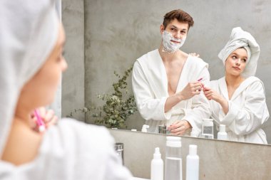 Güzel bir kadın, erkek arkadaşıyla tıraş olmak için pembe tıraş bıçağını paylaşıyor.