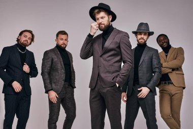 Sakallı Avrupalı erkekler ve smokinli bir Afrikalı poz veriyor.