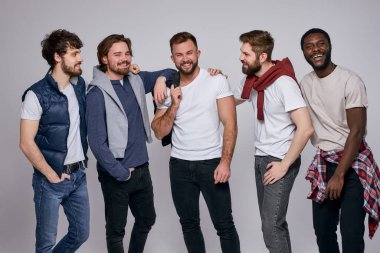 Kameraya poz veren şehirli gibi giyinmiş pozitif çeşitli erkekler.