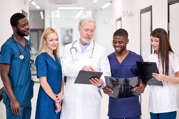 Beyaz üniformalı kıdemli doktor genç doktorlara danışmanlık yapıyor.