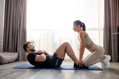 Genç kadın, erkeğin karın kaslarını geliştirmesine yardımcı oluyor.