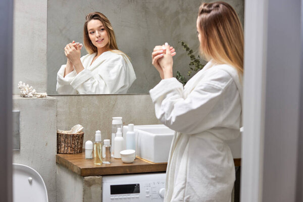 Женщина наносит увлажняющий крем на руки