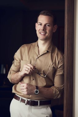 Zarif kahverengi gömlekli yakışıklı vahşi adam kameraya bakıyor.