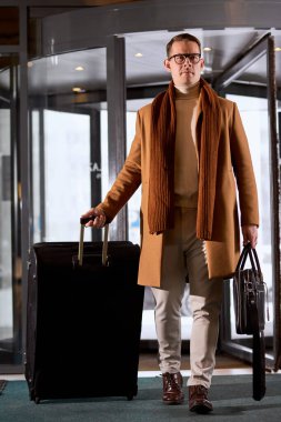 Zarif ceketli bir işadamı. Sürükleme bavulu ya da otel lobisine doğru yürüyen bir bavul..