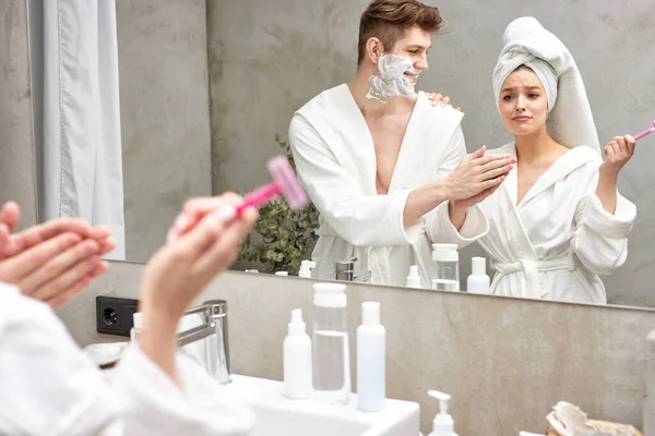 Güzel bir kadın, erkek arkadaşıyla tıraş olmak için pembe tıraş bıçağını paylaşıyor.