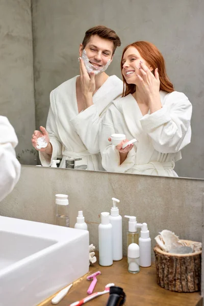 Mężczyzna i kobieta dbać o skórę twarzy, używać pianki i kremu — Zdjęcie stockowe