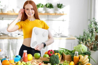 Güzel bir kadın, doğal güzelliği ve kızıl saçları var, gülümsüyor, kilolarla ayakta duruyor.