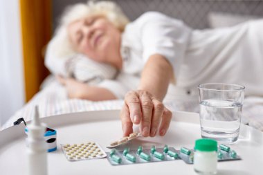 Hasta kişi yatakta yatarken ilaç alıyor.