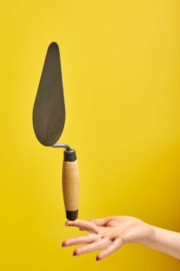 Kesilmiş erkek, beton bir duvarı kusurlardan, onarımlardan ve inşaatlardan temizlemek için parmağında spatula tutuyor.