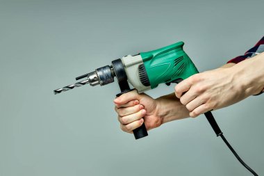 Kırpılmış erkek ellerinde yeşil elektrikli çekiç