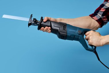Karşılık veren testere çelik dişli bıçakla. Ahşap işçiliği için elektrikli alet. mavi üzerine izole