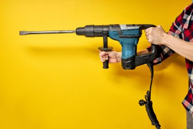 Sarı arka planda izole edilmiş inşaatçının ellerinde yeşil yumruklayıcı