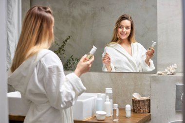 Çekici kadın nemlendirici damlalar koyuyor ve sağlıklı yüz derisi için güzellik ürünü kullanıyor.