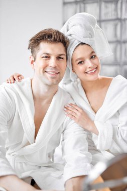 Yakışıklı bir adam ve bornozlu çekici bir kadın duştan sonra evde yatakta oturuyor.