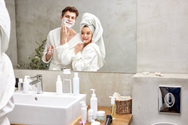 20-26 yetişkin çift eğleniyor, dişlerini fırçalamayı seviyor ve diğer sabah ameliyatlarını banyoda yapıyor.