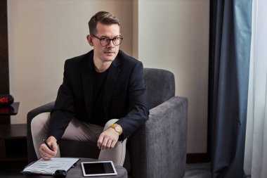 Takım elbiseli hoş bir adamın portresi. Işıkta tek başına çalışan notlar alıyor.