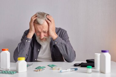 Mutfakta oturan üzgün yaşlı adam Masanın arkasında oturuyor