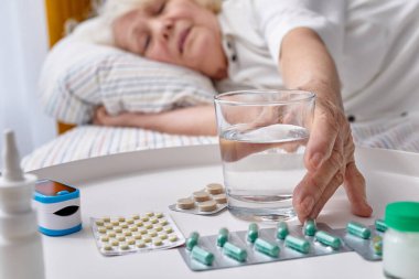 Sabah bir bardak taze su içen yaşlı bir kadının yakın plan fotoğrafı.