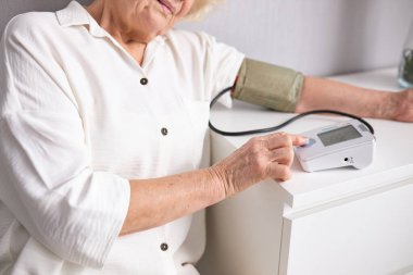 Kan basıncını elle ölçen yaşlı kadına yan bakış