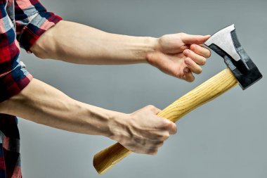 Tanımlanamayan adam baltanın keskinliğini parmak ile kontrol eder.